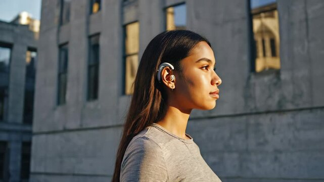 Young Woman Wearing Cochlear Implant Outdoors Facing Sideways in Bright Daylight Urban Setting
