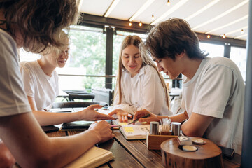 Fototapeta premium Students are working on the project. Group of young friends are in the cafe restaurant