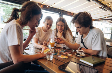 Having fun by playing the game by table. Group of young friends are in the cafe restaurant