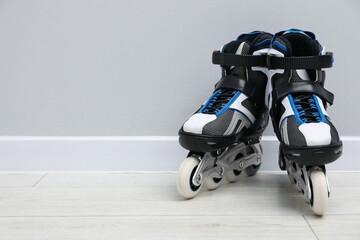 Pair of roller skates on floor near white wall, space for text