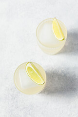 Refreshing detox citrus drink. Vitamin water with lime slices and ice cube on white table. Healthy,...