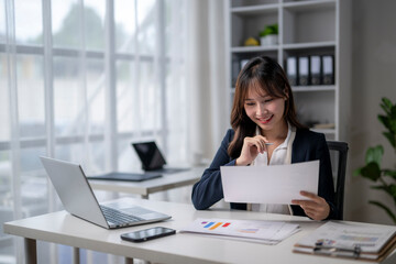 Businesswoman smiling and reviewing documents at office desk © Wasana
