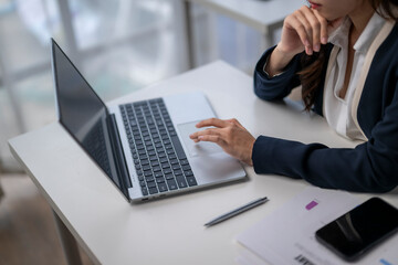 Businesswoman working on laptop in modern office: analyzing data and reports