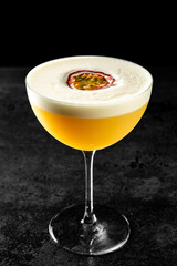 Elegant yellow cocktail with passion fruit garnish in a coupe glass, isolated on dark background. Fresh, frothy, and tropical drink for parties or summer menus