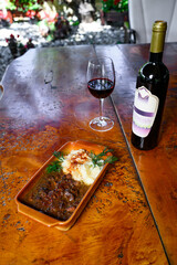 Venison stew with mashed potatoes with a bottle and a glass of wine