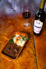 Venison stew with mashed potatoes with a bottle and a glass of wine