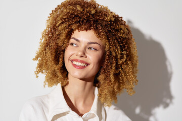 Smiling woman with curly hair against a light background, showcasing confidence and joy, ideal for...