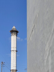 Mosque tower in the city against clear blue sky