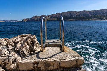 Metal handrail at the stairs leading to the sea, entry to the water via metal stairs KRK Baska...