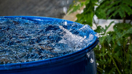 Rain water dropping into a blue drum close up shot