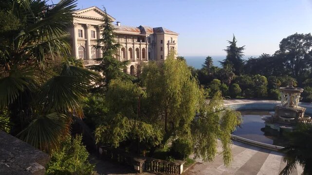 SOCHI - JUN 26, 2017: Large house with a pool and a fountain. The pool is surrounded by trees. The house is on a hill overlooking the ocean. abandoned sanatorium Dzerzhinsky in Sochi