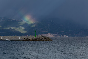 Dramatic sky after a storm, clouds over the Velebit Mountains in Croatia, a colorful rainbow breaks...