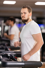 Man works out on a treadmill in a gym. Client of a fitness club performs a cardio warm-up