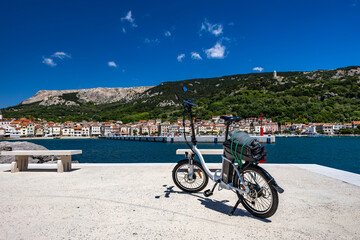 Fototapeta premium Cycling tour on the island of Baska, electric bike parked on a concrete platform by the beach in Baska