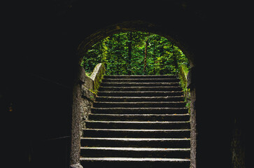 Salzburg in Austria. A staircase leading to a tunnel. The stairs are made of stone. The tunnel is dark and has a green canopy