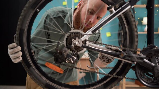 Young man checking bike wheel and repairing bicycle at home