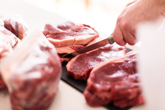 cutting a bulk butcher shop purchase into portions with knife