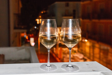 Two glasses of wine on the balcony ledge of a hotel in the summer evening, at night. Vacation time.