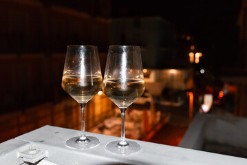 Two glasses of wine on the balcony ledge of a hotel in the summer evening, at night. Vacation time.
