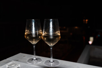 Two glasses of wine on the balcony ledge of a hotel in the summer evening, at night. Vacation time.