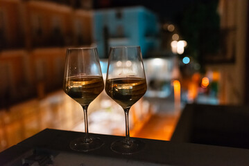 Two glasses of wine on the balcony ledge of a hotel in the summer evening, at night. Vacation time.