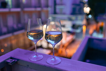 Two glasses of wine on the balcony ledge of a hotel in the summer evening, at night. Vacation time.