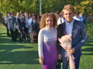 A man and a woman are standing in a field. The man is wearing a suit and the woman is wearing a...