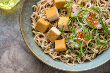 Close-up of ramen noodles with soy-marinated egg and smoked tofu cheese, horizontal shot, selective focus