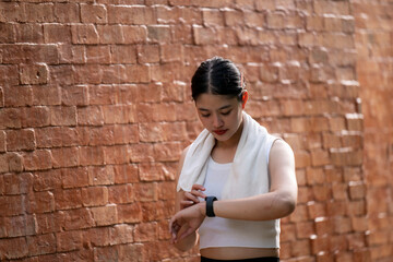 A woman wearing a white shirt and a towel is looking at her watch