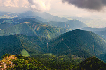 A mountain range with a cloudy sky. The mountains are covered in trees. The sky is cloudy and the sun is not visible