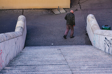 A man walks down a set of stairs. The stairs are made of concrete and are covered in graffiti