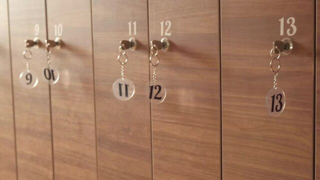 Wooden locker unit with multiple numbered doors, each equipped with a key for secure storage. Suitable for gym, school, or office settings. Elegant wood finish enhances interior space
