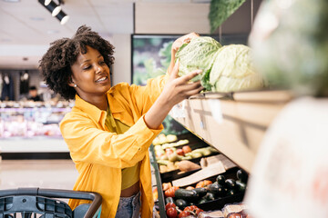 Young woman buying fresh vegetables in grocery store