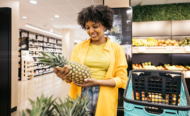 Customer choosing fresh pineapple in supermarket fruit and vegetable section