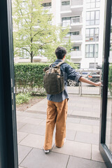 Young student girl is opening the door and leaving home in the morning