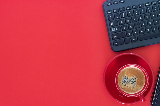 Modern workspace with coffee and wireless keyboard. Bright red background adds energy and contrast