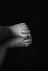 A black and white photo capturing the tiny feet of a newborn baby. The baby s toes are curled and...