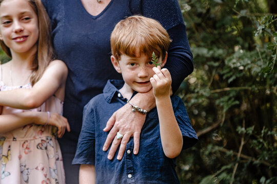 Young boy holding a piece of a fern leaf in bushland