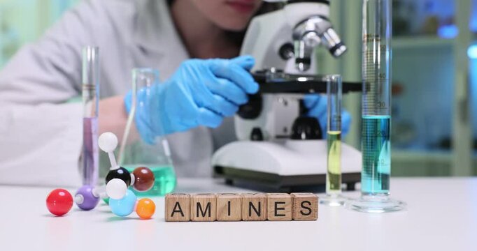 A lab technician carefully examining various samples related to amines with the use of a microscope