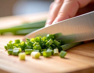 A sharp knife cuts fresh green onions on a wooden cutting board creating chopped scallions ready to use in cooking