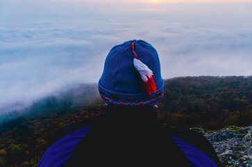 A person wearing a blue hat with a red feather on it. The hat is on a person's head