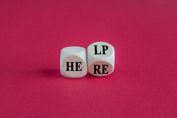 Turned a wooden cube and change words 'help' to 'here'. Beautiful pink background.