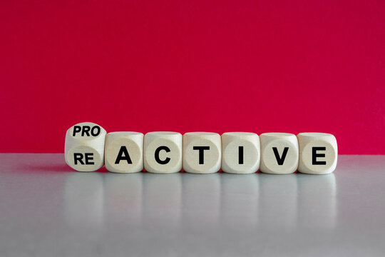Turned a dice and change the word reactive to proactive. Beautiful pink background, grey table. Business and reactive or proactive concept