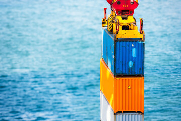 Blue cargo container loaded by the gantry crane on the container ship - port waters surrounds the...