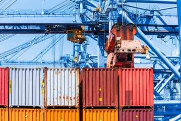 Colorful shipping containers stacked on a cargo ship's deck, positioned in front of large blue...