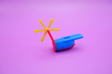 A colorful plastic whistle toy featuring a rotating yellow pinwheel on its tail. The whistle has a...