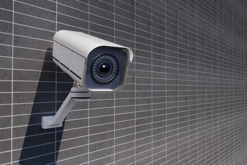 A white security camera is mounted on a wall