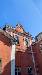 Sunlit terracotta church facade whispers ancient tales, evoking All Saints' Day reverence and...