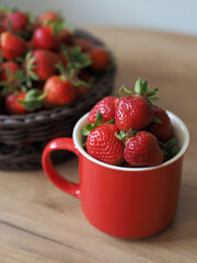 Ripe red strawberry in a mug and basket on the table
