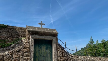 Ancient stone gateway crowned with a solitary cross, whispers of All Souls' Day and architectural...